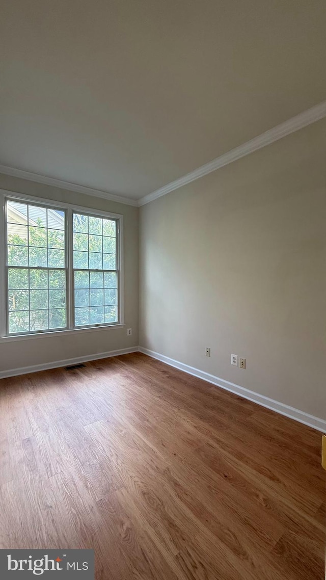 unfurnished room featuring crown molding, dark wood-style flooring, and baseboards