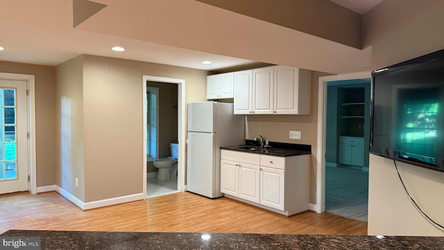 kitchen with freestanding refrigerator, light wood finished floors, dark countertops, white cabinetry, and recessed lighting
