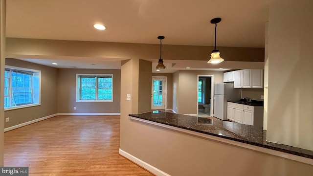 kitchen with freestanding refrigerator, light wood-style flooring, white cabinetry, decorative light fixtures, and a sink