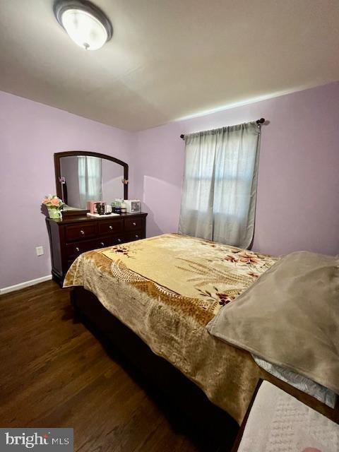 bedroom with baseboards and dark wood-style flooring