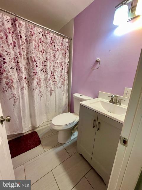 bathroom with tile patterned flooring, curtained shower, toilet, and vanity