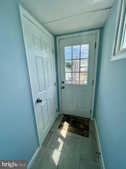 doorway to outside featuring baseboards and tile patterned flooring