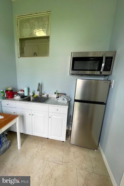 kitchen with baseboards, light countertops, white cabinetry, a sink, and stainless steel appliances