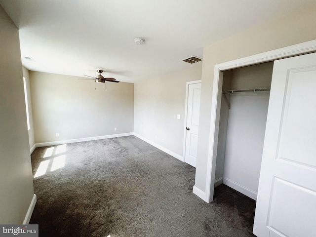 unfurnished bedroom with dark colored carpet, baseboards, visible vents, and a closet