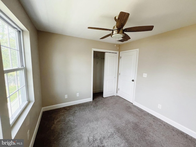 unfurnished bedroom with baseboards, multiple windows, carpet, and a closet