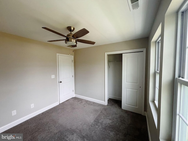 unfurnished bedroom featuring ceiling fan, visible vents, baseboards, a closet, and dark colored carpet