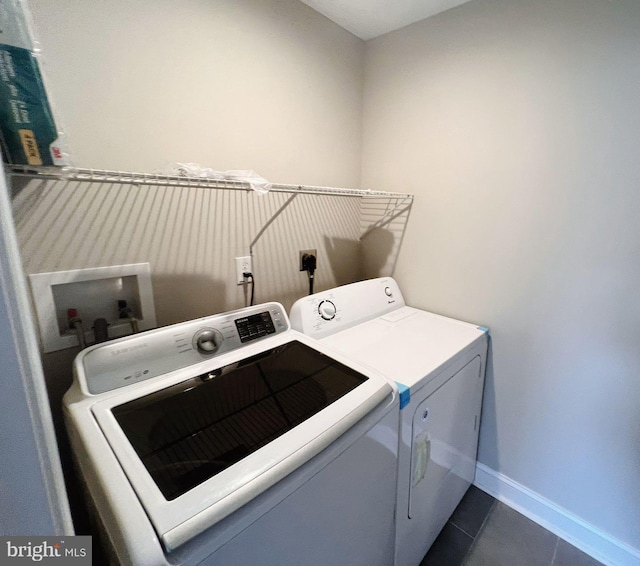 clothes washing area with laundry area, washer and clothes dryer, baseboards, and dark tile patterned flooring