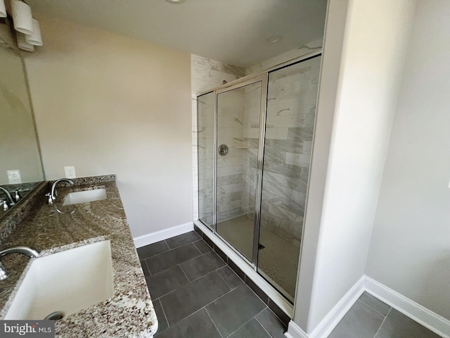 full bathroom featuring a sink, baseboards, a stall shower, and double vanity