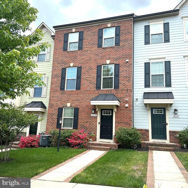 townhome / multi-family property with a front lawn, brick siding, and central AC