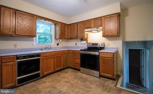 kitchen featuring electric range, dishwasher, a sink, under cabinet range hood, and brown cabinets