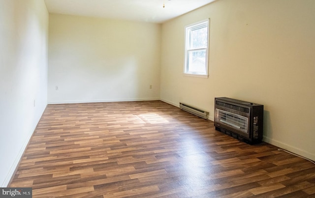 spare room featuring a baseboard radiator, wood finished floors, and baseboards