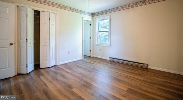 unfurnished bedroom with a baseboard heating unit, dark wood-type flooring, baseboards, and a closet