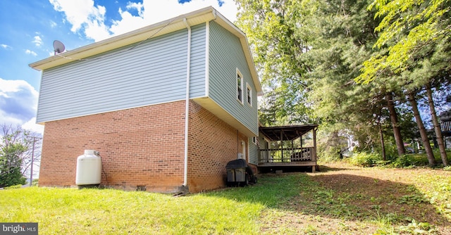 view of side of home with brick siding, a deck, and a lawn