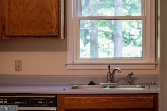 kitchen featuring a sink, dishwasher, brown cabinets, and light countertops