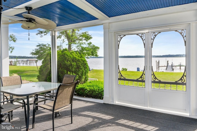 sunroom / solarium featuring a water view, a ceiling fan, and outdoor dining space