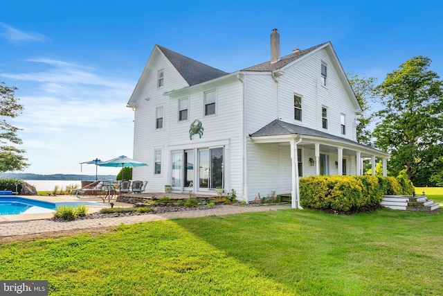 view of side of property featuring an outdoor pool, a patio area, a yard, and a chimney