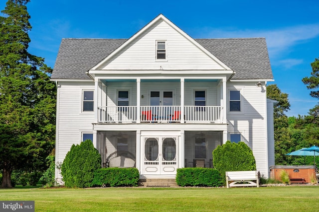 rear view of property with a lawn, french doors, a hot tub, and a balcony
