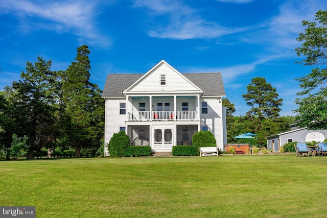 back of property with a lawn, roof with shingles, and a balcony