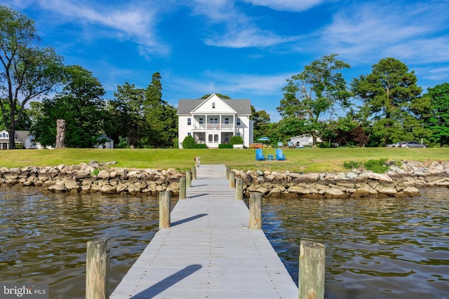 dock area with a lawn, a water view, and a balcony