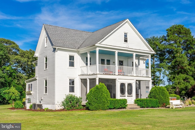 view of front of property with central AC unit, a shingled roof, a balcony, and a front yard