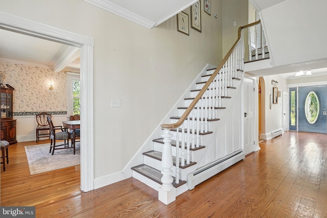stairway featuring crown molding, baseboard heating, and hardwood / wood-style flooring