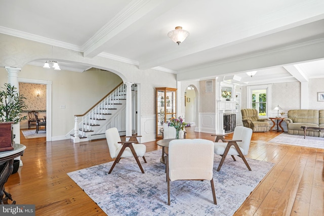 living area featuring arched walkways, beamed ceiling, and hardwood / wood-style floors