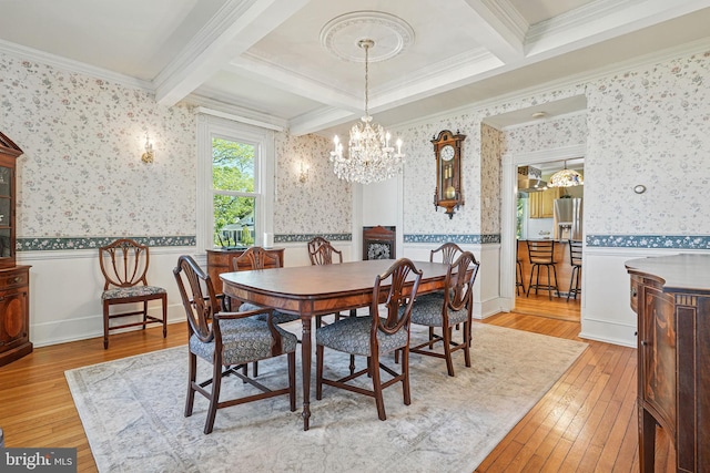 dining room with a chandelier, ornamental molding, light wood finished floors, and coffered ceiling
