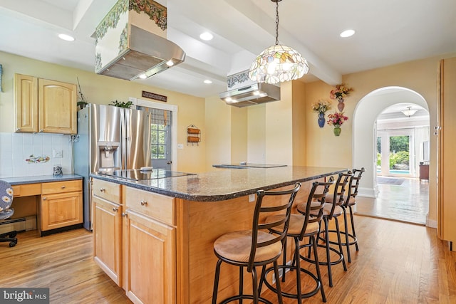 kitchen with arched walkways, a wealth of natural light, a kitchen island, and black electric cooktop