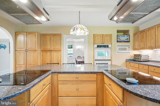 kitchen featuring white appliances, extractor fan, under cabinet range hood, arched walkways, and dark stone countertops
