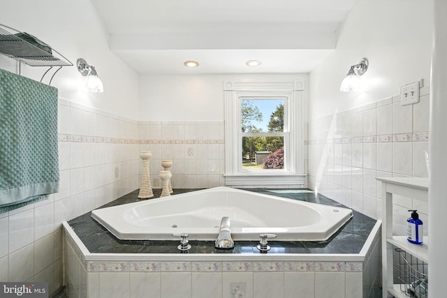 full bath featuring a jetted tub and tile walls