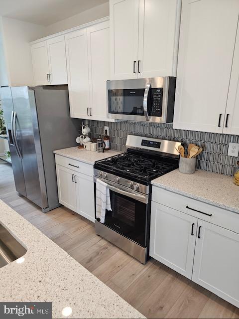 7304 Roxy Run, Clinton, MD 20735 - kitchen featuring light wood-type flooring, appliances with stainless steel finishes, white cabinets, and light stone countertops