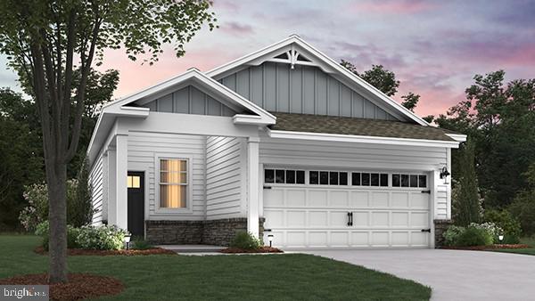 craftsman house with board and batten siding, an attached garage, driveway, and a front yard