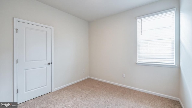carpeted empty room featuring baseboards