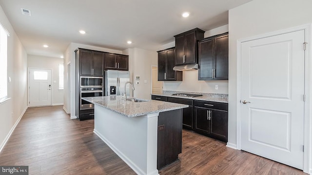 kitchen with under cabinet range hood, appliances with stainless steel finishes, dark wood-style floors, and a sink