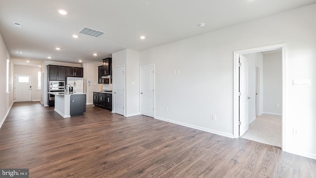 unfurnished living room featuring visible vents, baseboards, dark wood-type flooring, recessed lighting, and a sink