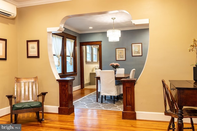 dining room with arched walkways, crown molding, a wall mounted AC, and wood finished floors