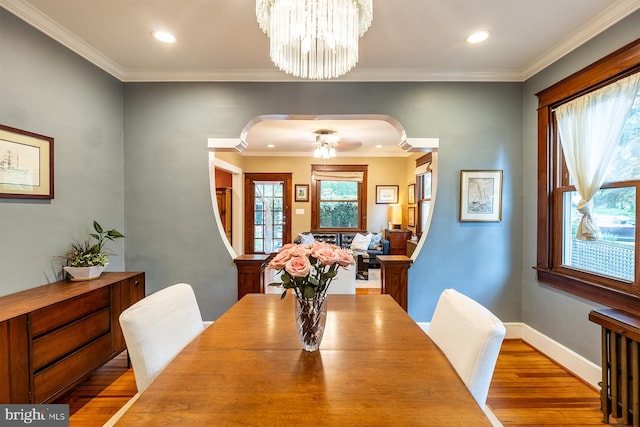 dining room with arched walkways, ornamental molding, recessed lighting, and wood finished floors