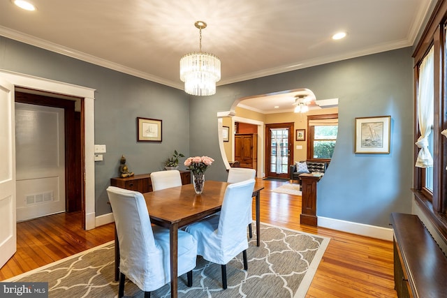 dining space with light wood-style flooring, arched walkways, and visible vents