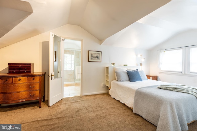 carpeted bedroom with lofted ceiling, multiple windows, and ensuite bathroom