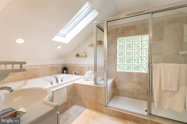 full bath with a stall shower, tile patterned flooring, lofted ceiling with skylight, and a garden tub