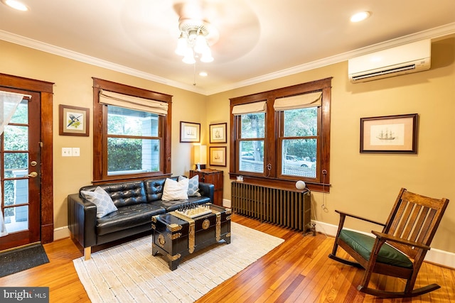 sitting room featuring light wood finished floors, a wall mounted air conditioner, baseboards, and radiator heating unit