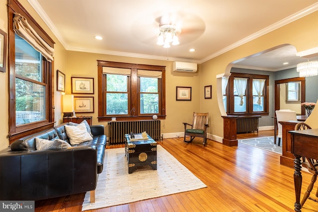 living area with radiator, plenty of natural light, arched walkways, and hardwood / wood-style flooring