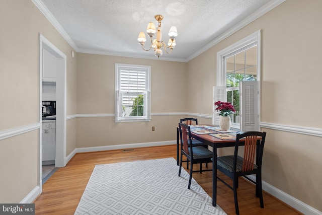 412 Linda Ave, Linthicum Heights, MD 21090 - dining area with a chandelier, light wood finished floors, a textured ceiling, crown molding, and baseboards
