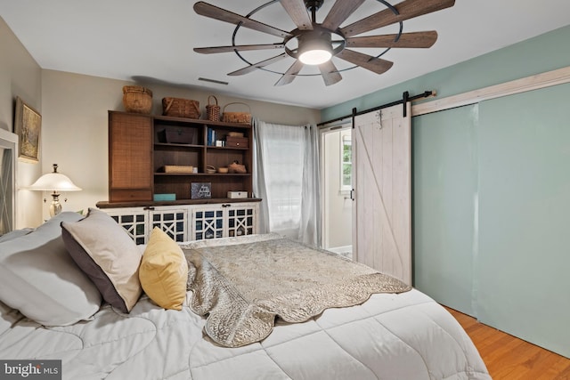 8543 Ingleton Rd, Easton, MD 21601 - bedroom featuring wood finished floors, a barn door, a closet, and a ceiling fan