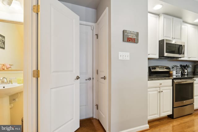 kitchen with recessed lighting, light wood-style flooring, white cabinetry, and stainless steel appliances