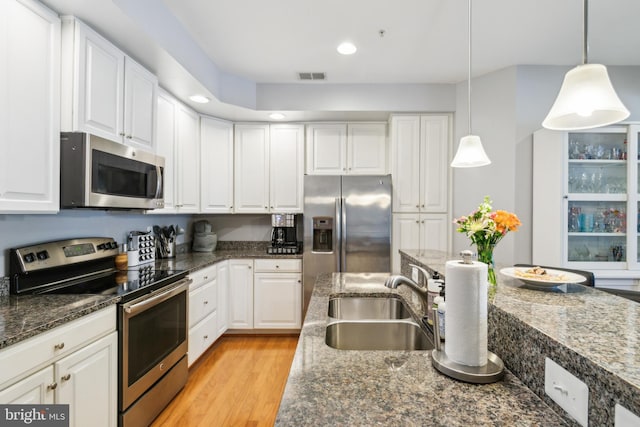 kitchen with white cabinets, a sink, light wood-style floors, stainless steel appliances, and visible vents