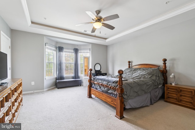 carpeted bedroom featuring a raised ceiling, a ceiling fan, baseboards, visible vents, and ornamental molding