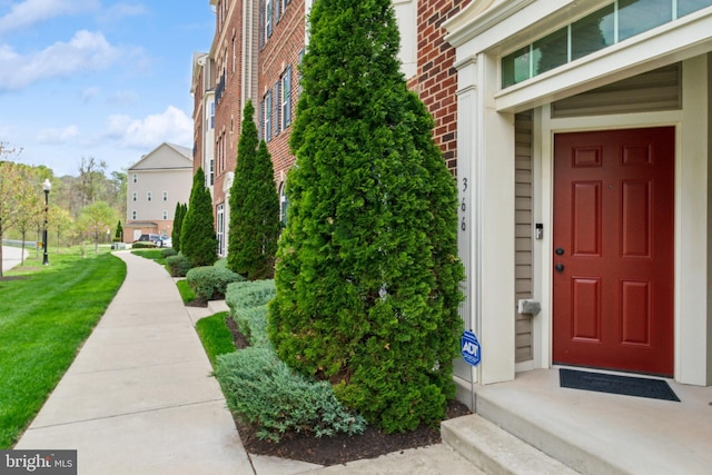 view of exterior entry featuring brick siding and a yard