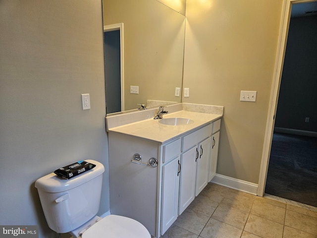 half bath with toilet, tile patterned floors, baseboards, and vanity