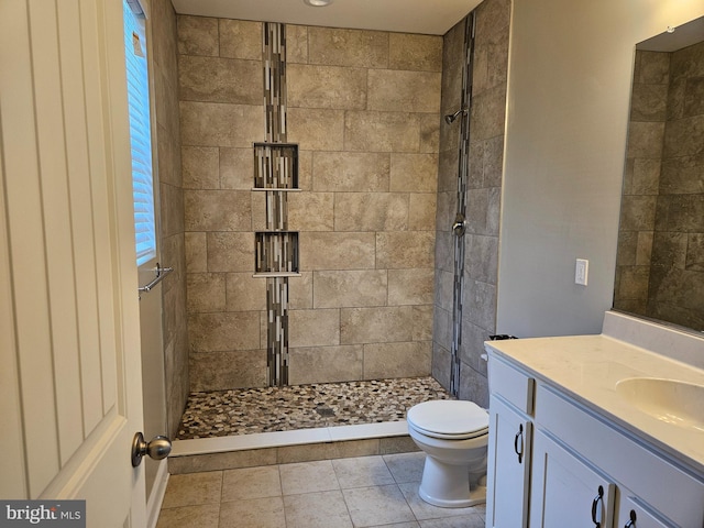 bathroom with vanity, tile patterned floors, a tile shower, and toilet